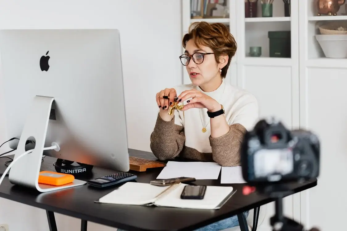 A woman teaching online sat behind a computer screen